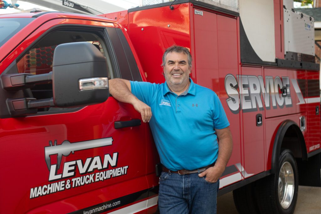 Brian standing next to red Service truck