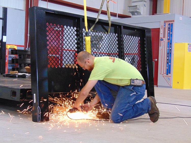 worker using grinder on truck liftgate